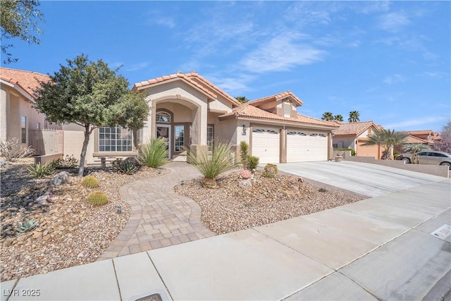 mediterranean / spanish-style house with stucco siding, a tiled roof, concrete driveway, and an attached garage