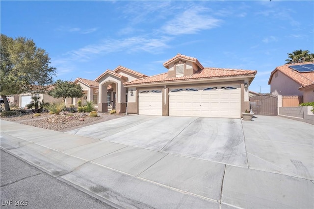 mediterranean / spanish-style house with a gate, stucco siding, concrete driveway, a garage, and a tiled roof