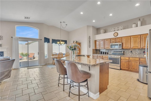 kitchen with visible vents, stainless steel appliances, a kitchen breakfast bar, tasteful backsplash, and a chandelier