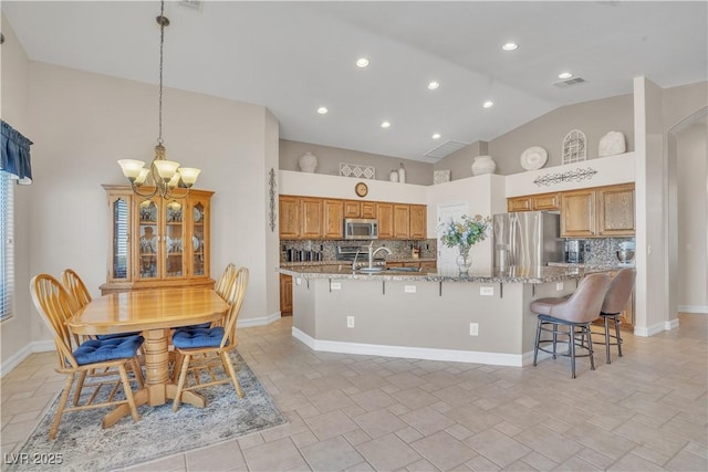 kitchen with visible vents, a large island with sink, appliances with stainless steel finishes, high vaulted ceiling, and a sink