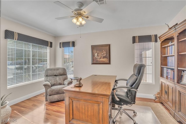 office space featuring baseboards, visible vents, light wood finished floors, and ceiling fan