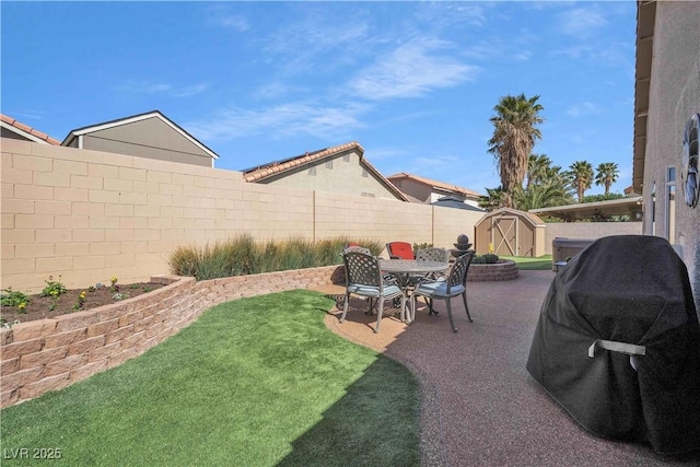 view of yard with an outbuilding, a patio area, a storage unit, and a fenced backyard