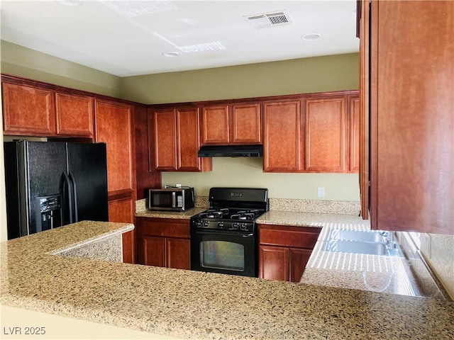 kitchen with visible vents, under cabinet range hood, brown cabinets, black appliances, and a sink