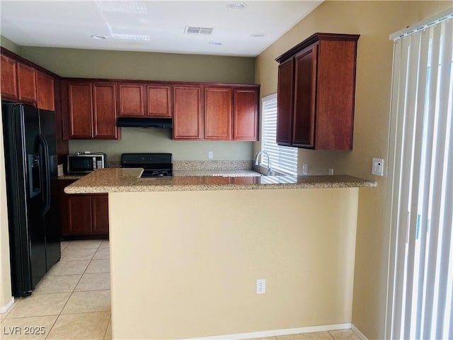 kitchen featuring visible vents, under cabinet range hood, a peninsula, light tile patterned flooring, and black appliances