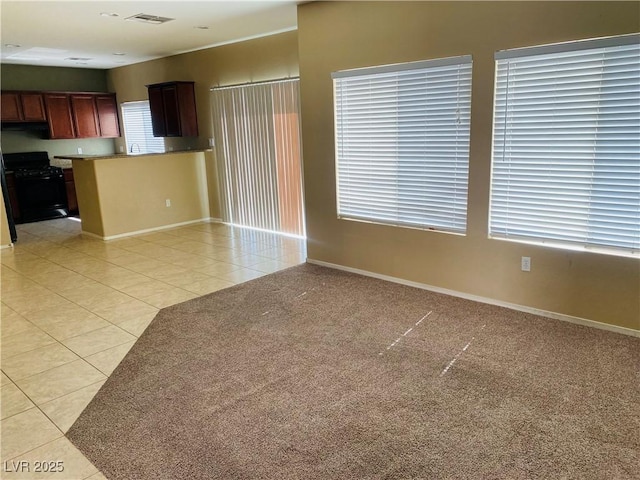 unfurnished living room with visible vents, light carpet, baseboards, and light tile patterned flooring