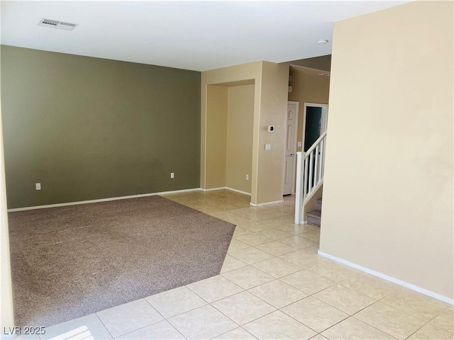 spare room with stairs, light tile patterned floors, baseboards, and visible vents