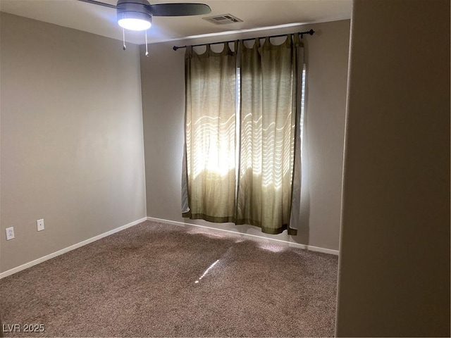 carpeted spare room featuring a ceiling fan, visible vents, and baseboards