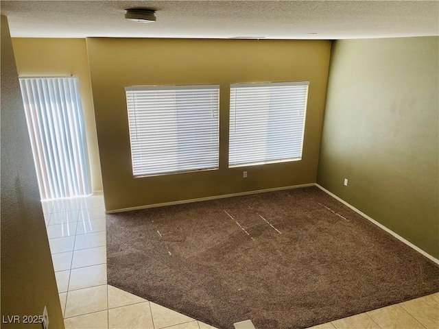 tiled empty room featuring baseboards, carpet, and a textured ceiling