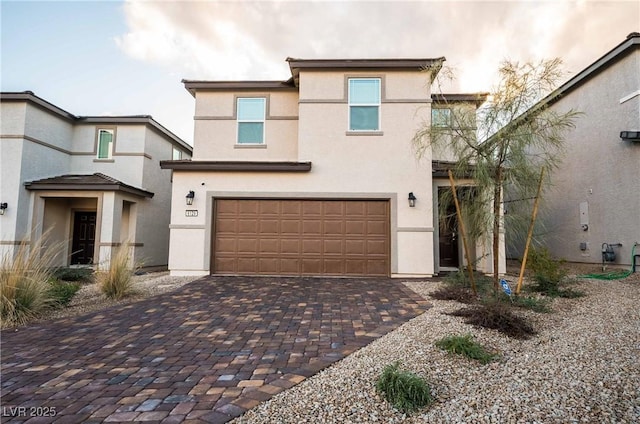 view of front of property featuring stucco siding, decorative driveway, and an attached garage