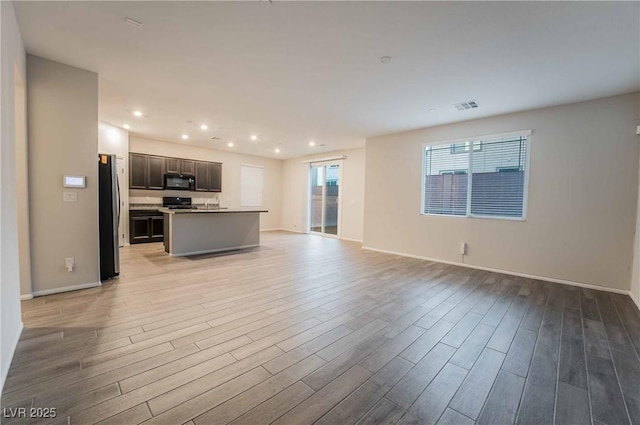 unfurnished living room with recessed lighting, visible vents, light wood finished floors, and baseboards