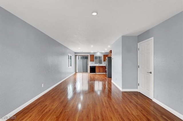 unfurnished living room with baseboards and wood finished floors