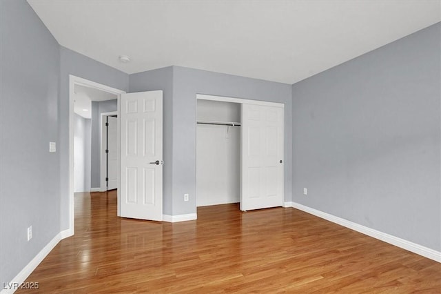 unfurnished bedroom featuring light wood finished floors, a closet, and baseboards