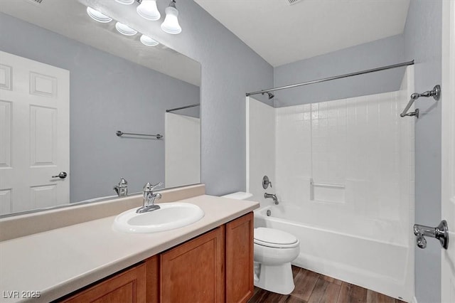 bathroom with vanity, toilet, wood finished floors, and shower / bathtub combination