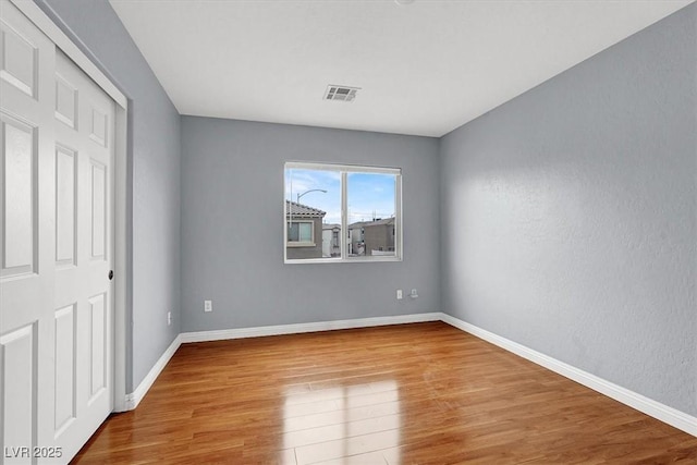 unfurnished bedroom with wood finished floors, visible vents, and baseboards