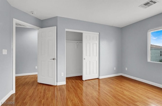 unfurnished bedroom featuring visible vents, baseboards, a closet, and light wood finished floors