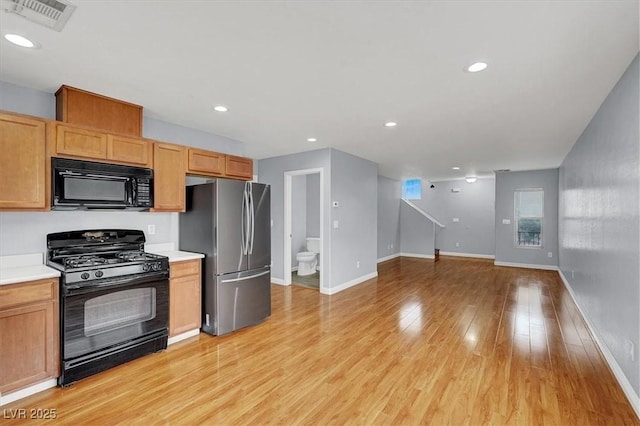 kitchen featuring light wood-type flooring, visible vents, black appliances, open floor plan, and light countertops