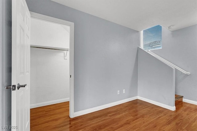 unfurnished bedroom featuring a closet, baseboards, and wood finished floors