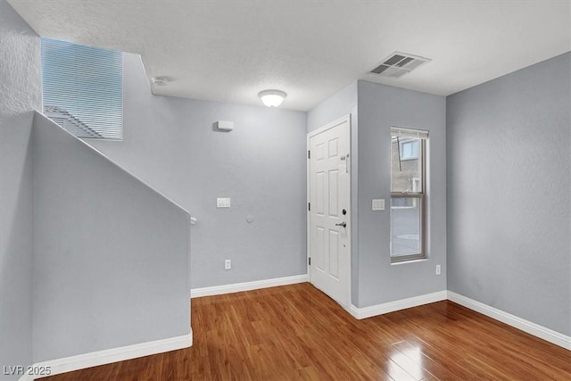 entryway with wood finished floors, visible vents, and baseboards