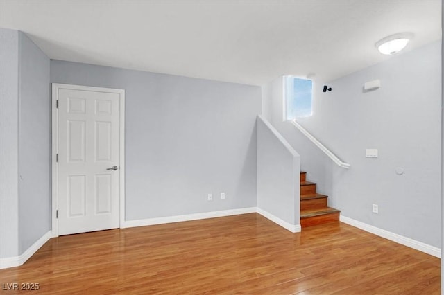 unfurnished living room featuring light wood-type flooring, baseboards, and stairway