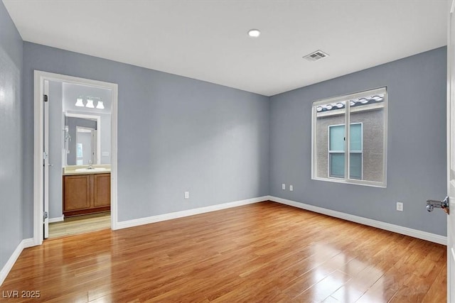 spare room featuring a sink, light wood-type flooring, and baseboards