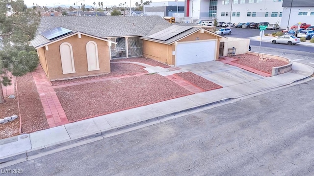 view of front of property with stucco siding, roof mounted solar panels, roof with shingles, and concrete driveway