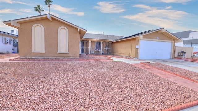 ranch-style house with solar panels, concrete driveway, an attached garage, and stucco siding