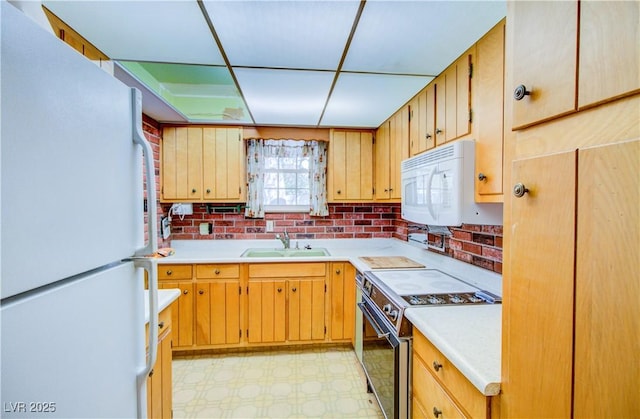 kitchen featuring a sink, white appliances, light floors, and light countertops