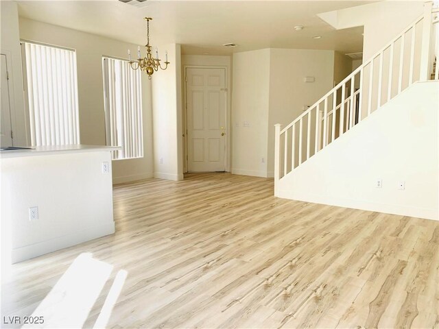 interior space with visible vents, baseboards, stairway, an inviting chandelier, and wood finished floors