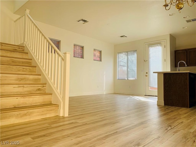 unfurnished living room with visible vents, light wood finished floors, and stairway