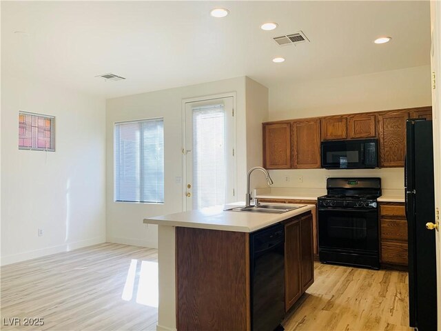 kitchen with visible vents, black appliances, a sink, light wood-style floors, and light countertops