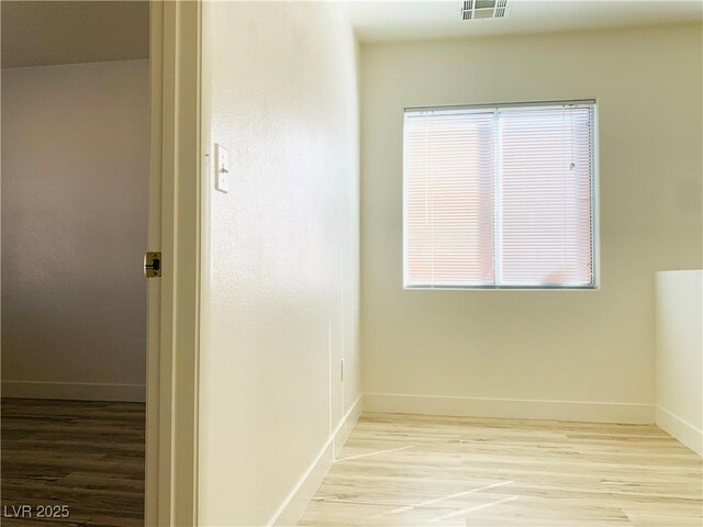 unfurnished room with visible vents, baseboards, and wood finished floors