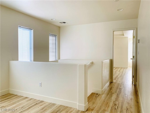 unfurnished room with visible vents, light wood-type flooring, and baseboards