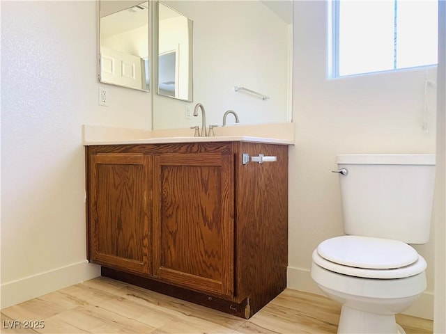 half bath with baseboards, toilet, wood finished floors, and vanity