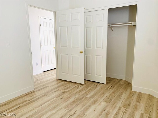 unfurnished bedroom featuring a closet, baseboards, and wood finished floors