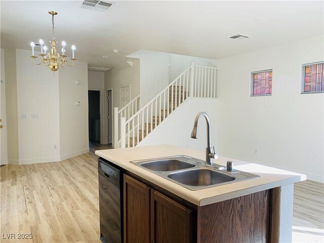 kitchen with visible vents, a sink, hanging light fixtures, black dishwasher, and light wood-style floors