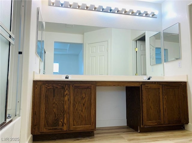 bathroom featuring a washtub, vanity, a shower, and wood finished floors