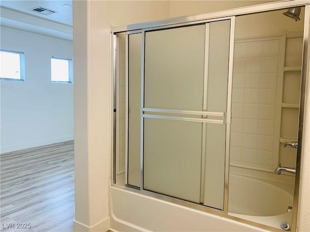 full bathroom featuring visible vents, enclosed tub / shower combo, baseboards, and wood finished floors