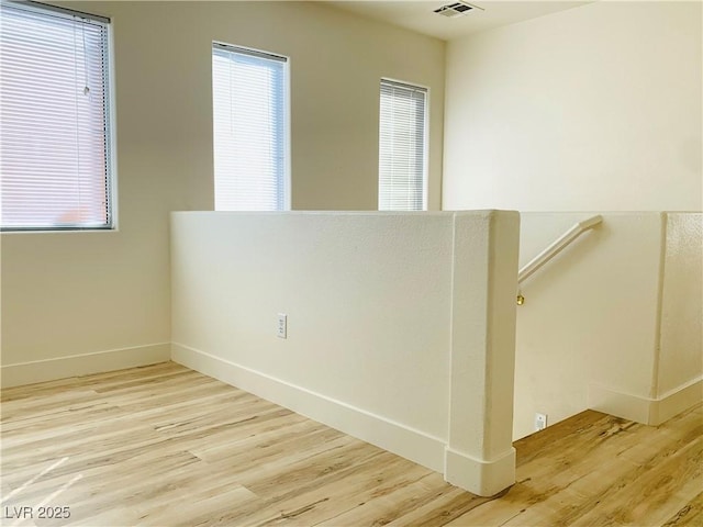 unfurnished room with wood finished floors, visible vents, and baseboards