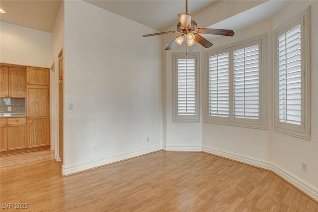 spare room with light wood-type flooring, baseboards, and ceiling fan