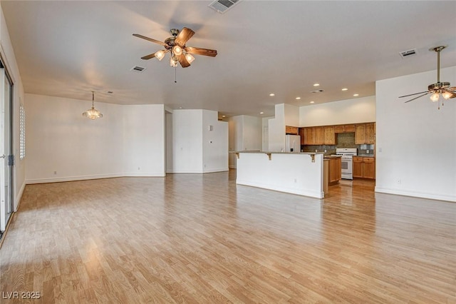 unfurnished living room with light wood-style flooring, visible vents, and ceiling fan