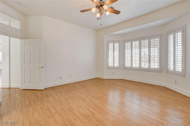 spare room with light wood-style flooring, a ceiling fan, and baseboards