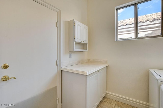 washroom featuring washer / clothes dryer, light tile patterned flooring, cabinet space, and baseboards