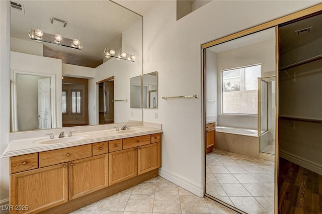 bathroom with visible vents, double vanity, a bath, tile patterned floors, and a sink