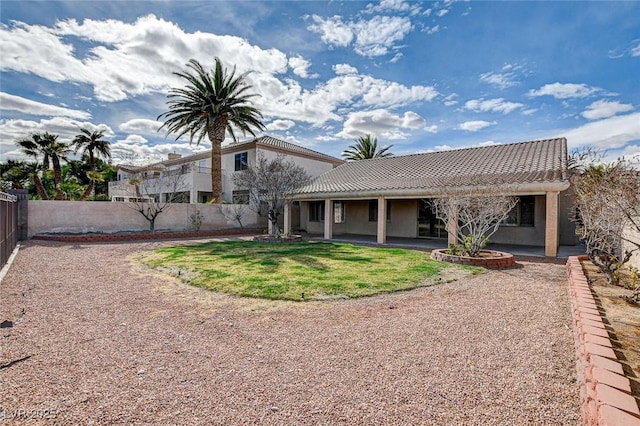 back of house featuring fence, stucco siding, a tile roof, a patio area, and a lawn