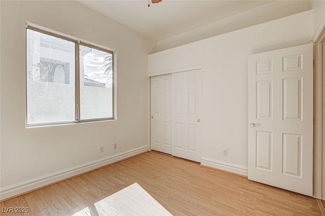 unfurnished bedroom with multiple windows, baseboards, and light wood finished floors