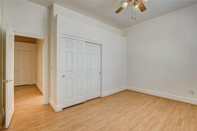 unfurnished bedroom with light wood-style flooring, a ceiling fan, baseboards, and a closet