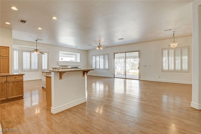 kitchen featuring open floor plan, a kitchen breakfast bar, visible vents, and light wood-type flooring