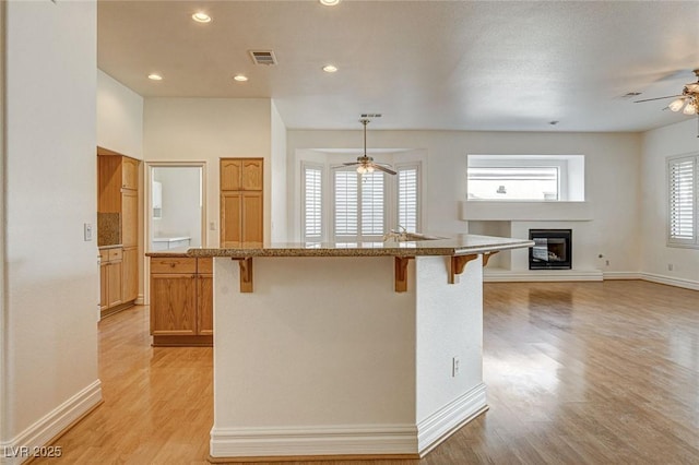 kitchen with visible vents, a kitchen breakfast bar, a center island, and a glass covered fireplace