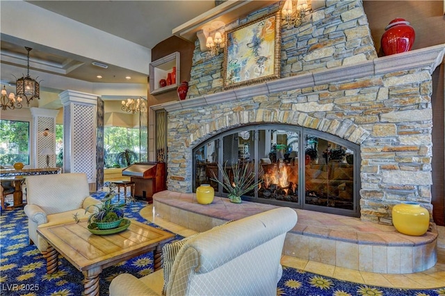 living room with a stone fireplace, tile patterned floors, a notable chandelier, and a healthy amount of sunlight