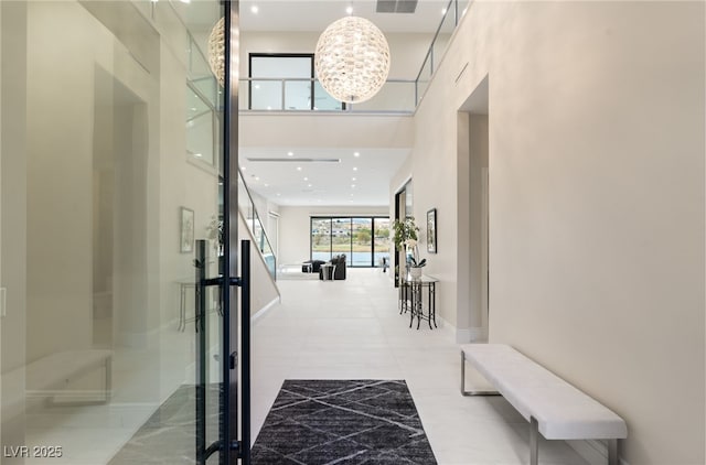 corridor featuring visible vents, baseboards, recessed lighting, an inviting chandelier, and a towering ceiling